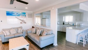 A modern living room with two sofas, a coffee table, and a kitchen area with white cabinets and a countertop. - Paradise Sands 5bed/3 bath+home office Sleeps 13  (Murrells Inlet)