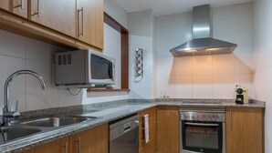 Una cocina moderna con armarios de madera, un lavamanos de acero inoxidable, un microondas, una estufa y una campana extractora.