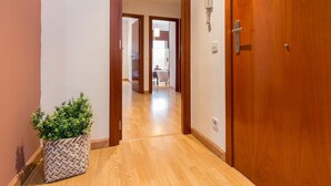 Un pasillo con suelo de madera, una planta en maceta y una puerta de madera.