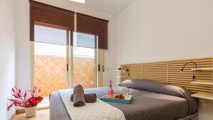 Un dormitorio moderno con una cama, una mesita de noche, una ventana con persianas y vistas al exterior.