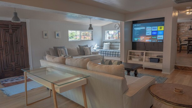 Una sala de estar moderna con una mesa de centro de vidrio, un sofá y un televisor que muestra servicios de transmisión.
