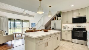 Uma cozinha moderna com armários brancos, eletrodomésticos de aço inoxidável e uma ilha grande.
