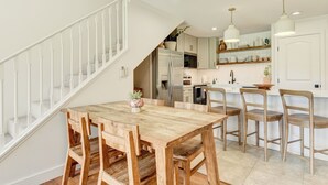 Uma cozinha moderna com uma mesa de jantar de madeira, armários brancos e uma escada que leva a outro nível.