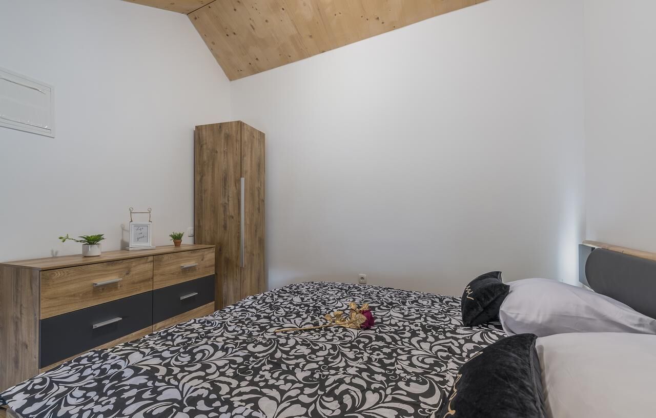 A bedroom with a bed, a wooden wardrobe, and a dresser.