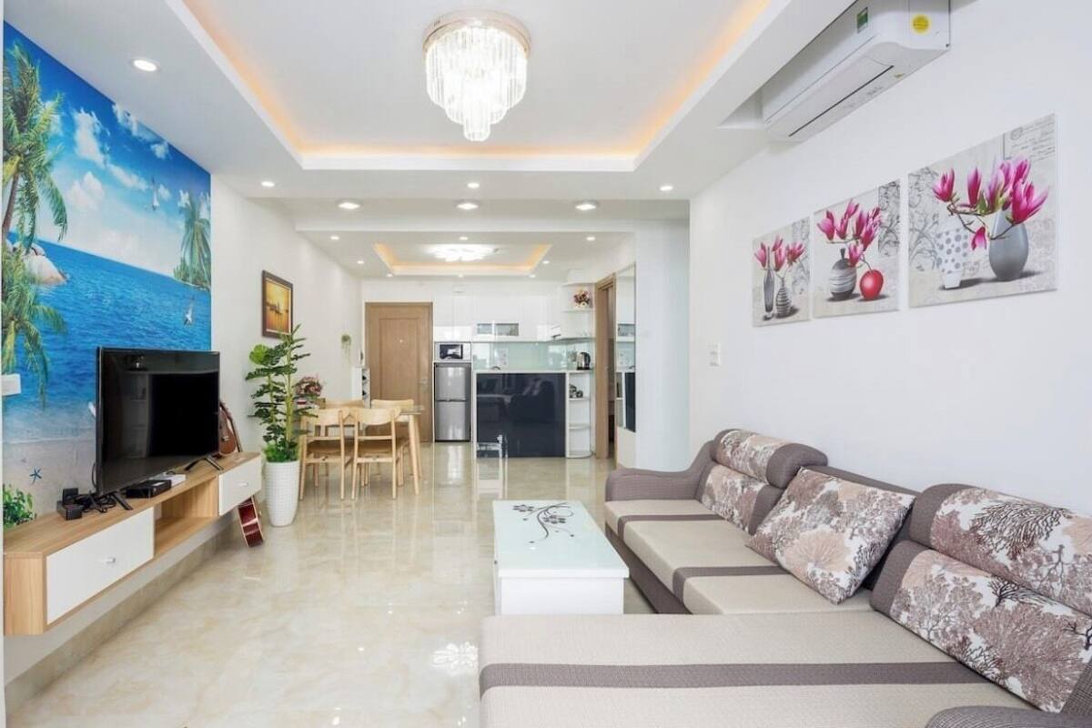 A modern living room with a flat-screen TV, a sofa, a coffee table, and a dining area.