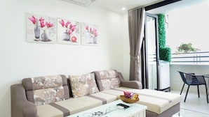 A modern living room with a sofa, a coffee table, and artwork on the wall. - Muong Thanh Apartment (Da Nang)
