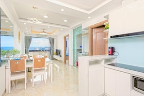 A modern kitchen with a built-in oven, a coffee maker, and a view of the sea.