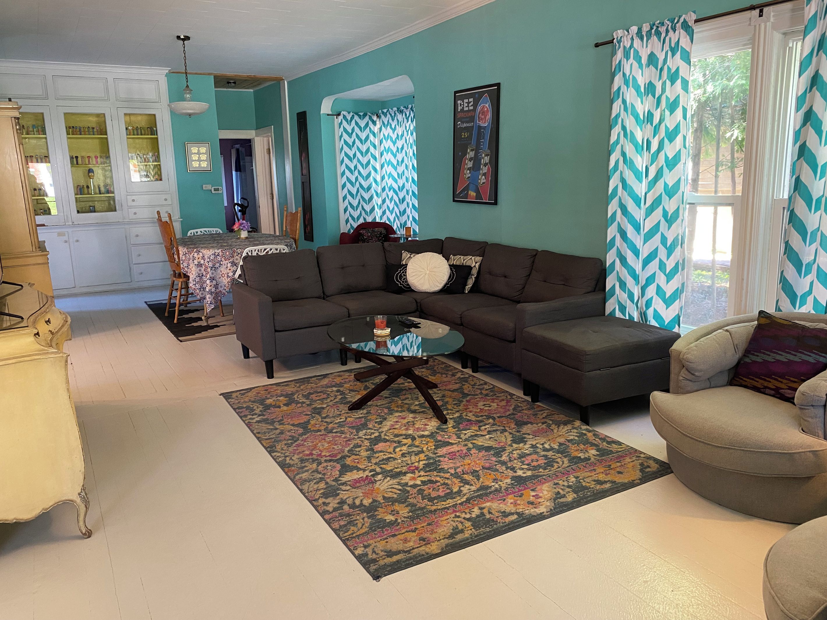 A living room with a sectional sofa, a glass coffee table, and a patterned rug.