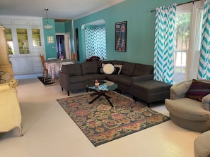 A living room with a sectional sofa, a glass coffee table, and a patterned rug.