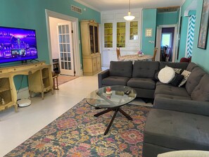 Una sala de estar con televisión, sofá, mesa de centro y un tapete estampado.