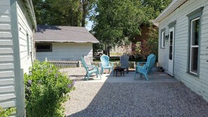 A covered patio area with outdoor seating, including several Adirondack chairs and a table.