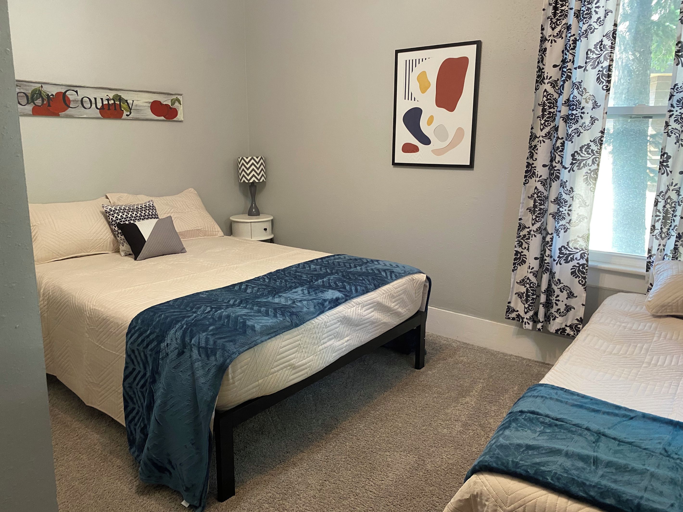 Une chambre à coucher avec un lit, une table de chevet, une lampe et un élément décoratif mural.