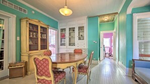 Comedor con mesa y sillas de madera, un aparador con puertas de vidrio y un pasillo que conduce a otra habitación.
