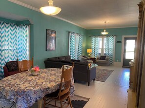 Ein Wohnzimmer mit Esstisch, Sofas und einer Chandelier.