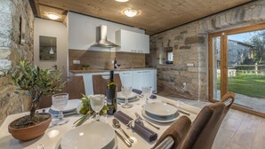 A dining area with a stone wall, wooden ceiling, and a view of the garden. - Aquileia Residence # 2- peaceful, private garden, large pool, close to Grožnjan (Grožnjan)