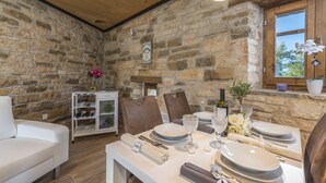 A dining area with stone walls, a wooden ceiling, and a window with a view. - Aquileia Residence # 2- peaceful, private garden, large pool, close to Grožnjan (Grožnjan)