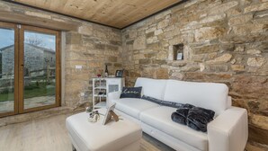 Una habitación acogedora con una pared de piedra, un sofá blanco y un ventanal que da al exterior.