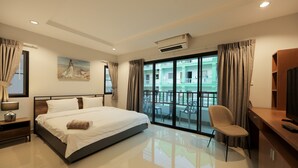 Una habitación de hotel moderna con una cama grande, un escritorio, una silla y un balcón con vistas a edificios.