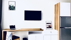 Una cocina moderna con un escritorio de madera, una computadora portátil, un refrigerador y cuadros en la pared.
