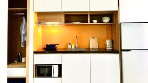 Una cocina compacta con armarios blancos, un microondas, un fregadero y un refrigerador.