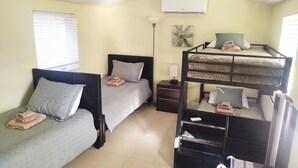 Un dormitorio con literas, una mesita de noche, una lámpara y un aire acondicionado.