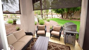 A covered patio with a sofa, two chairs, a table, and a grill. - PRIVATE GATED VACATION CONDO  WITH HEATED POOL, SPA, FITNESS ROOM, PATIO, GARAGE (Mesa)