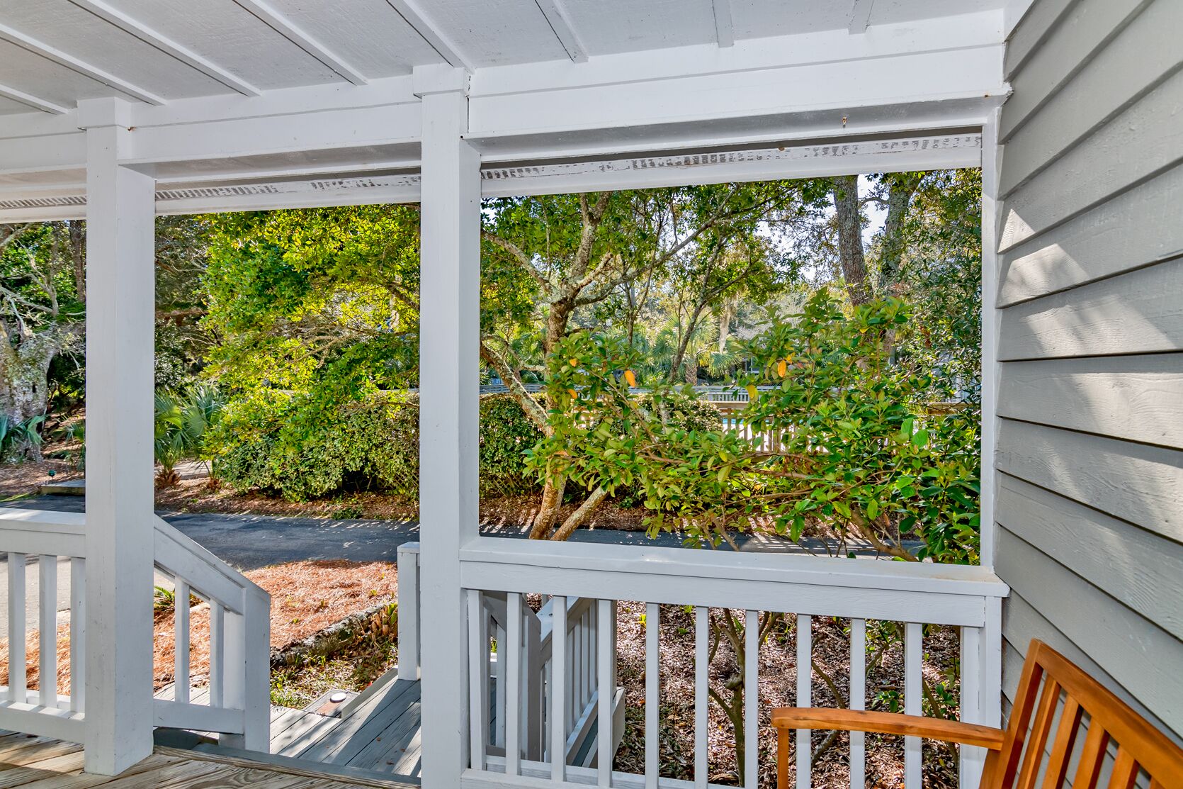 A covered porch with white railings and a wooden bench.