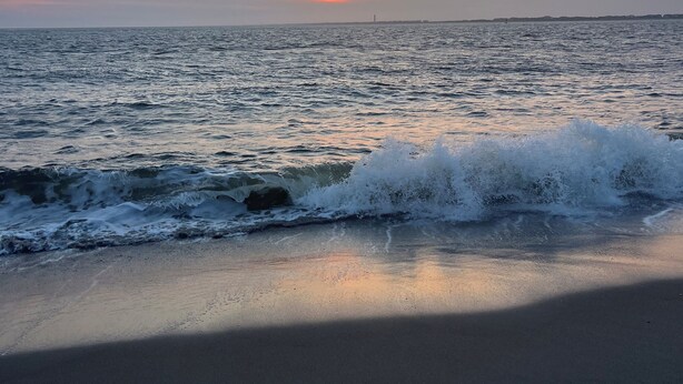 A beach with waves at the shore and a distant horizon.