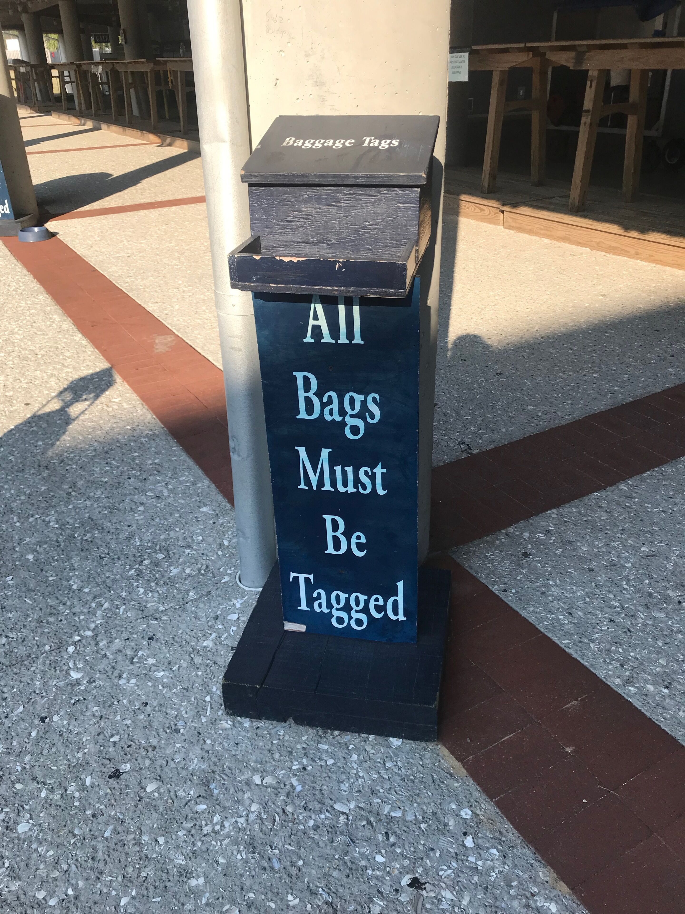 A sign that reads "All Bags Must Be Tagged" on a black box.