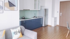 Een moderne keuken met witte kasten, een roestvrijstalen koelkast en een grijze bank met een kussen.