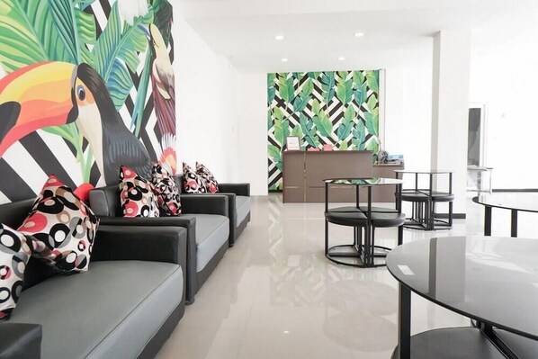 Un espace de détente moderne comprenant un ensemble de canapés, une table ronde et une grande fresque murale abstraite.
