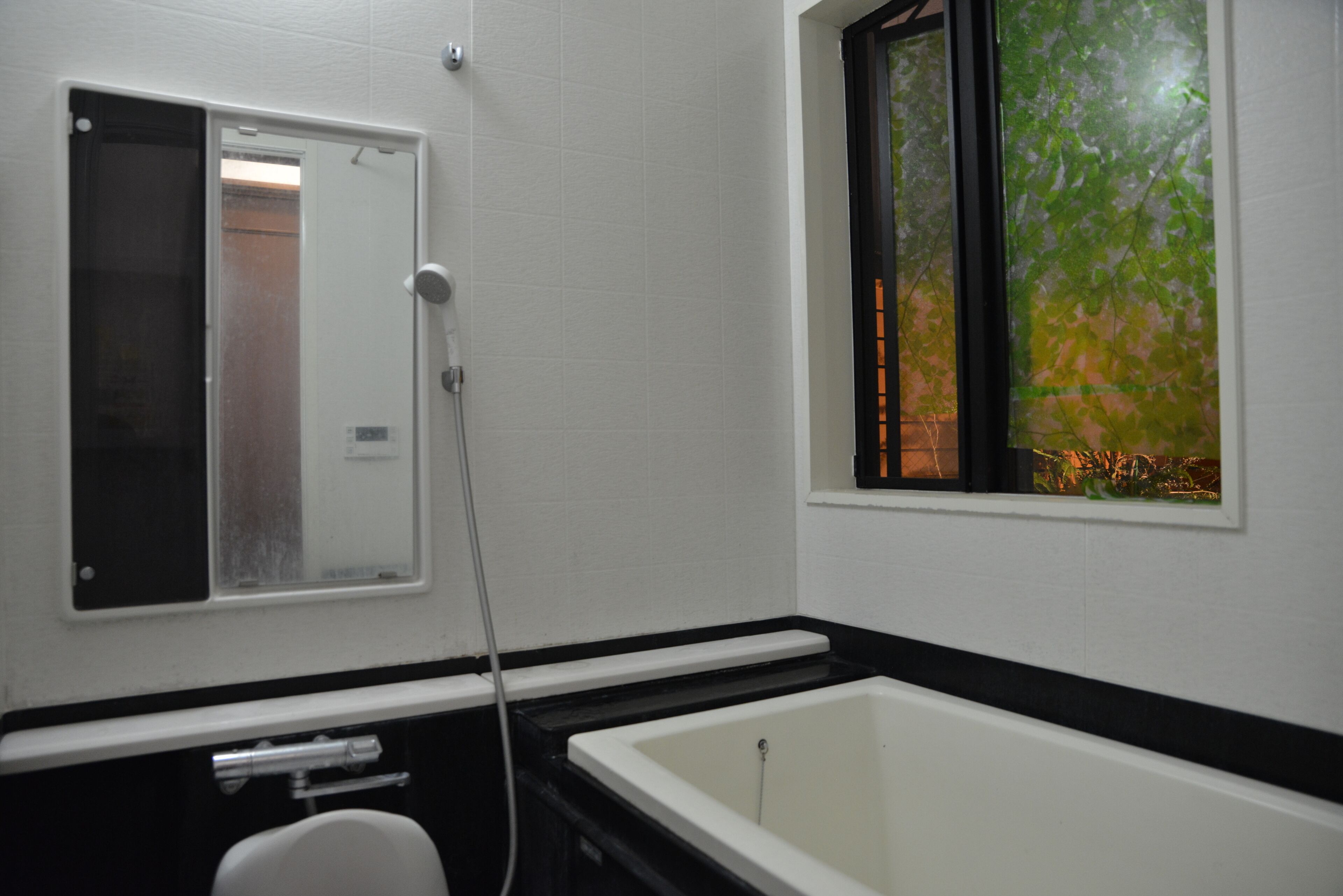 Een badkamer met een bad, een toilet en een raam met uitzicht op bomen.