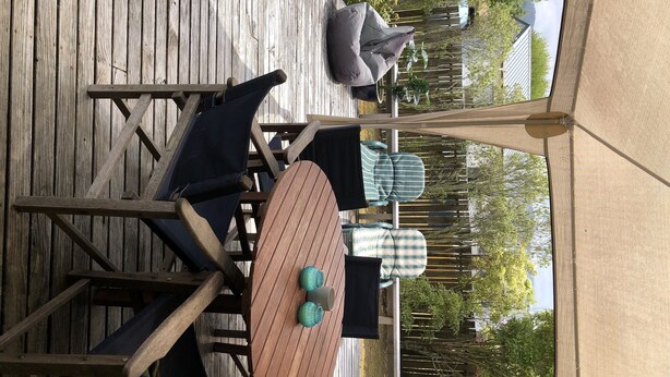 A wooden deck with outdoor furniture, including a table and chairs, and a canopy. - Pauanui Beach House. (Pauanui)