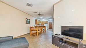 A living room with a TV, a sofa, and a dining area with chairs and a table. - Casa Blanca CB-102 Let Me Count The Waves Beautiful View Condo (Puerto Peñasco)
