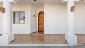 A clean, white-walled hallway with a wooden door and a window. - Casa Blanca CB-102 Let Me Count The Waves Beautiful View Condo (Puerto Peñasco)