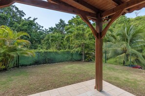 Un espacio al aire libre cubierto con suelo de baldosas, rodeado de exuberante vegetación y palmeras.