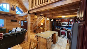 A cozy cabin interior with a living area, a kitchen, and a staircase. - 🏞Secluded Log Cabin Near Wisconsin Dells & Wisconsin River • Fireplace • Ski 🏕 (Lyndon Station)