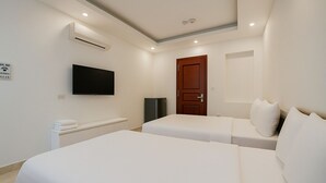 A hotel room with two beds, a TV, a wooden door, and an air conditioning unit. - Lakeside House - Hanoi (Hanoi)