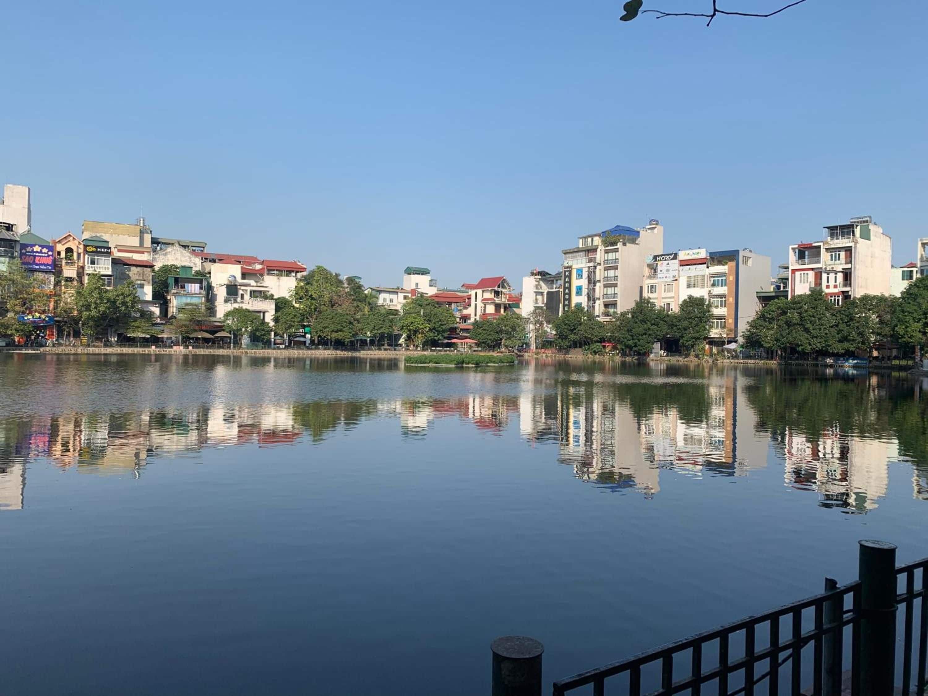 Un río tranquilo que refleja edificios, un cielo despejado y un puente peatonal.