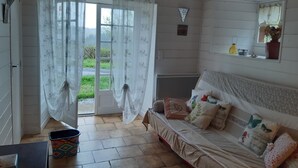 A cozy room with a bed, a window with curtains, a radiator, and a small shelf with items.