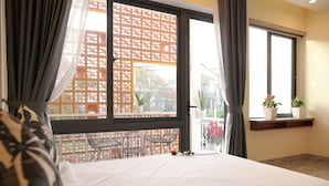 A bedroom with a large window, a bed, a small table, and a potted plant. - Lam Garden Boutique Homestay (Hue)