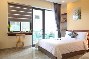 Een hotelkamer met een bed, een bureau met een stoel, een raam met zonwering en een balkon met stoelen.