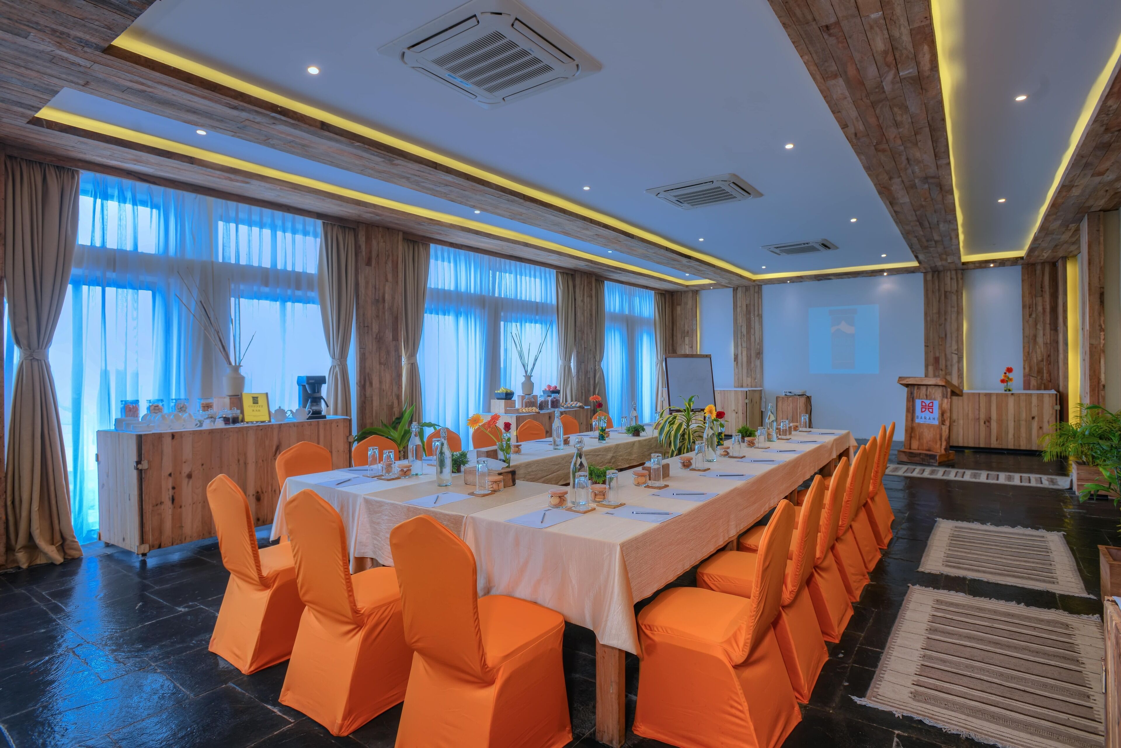 A conference room with a long table, orange chairs, and a wooden reception desk.