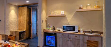 Una cocina compacta con microondas integrado, un refrigerador pequeño y armarios de madera.