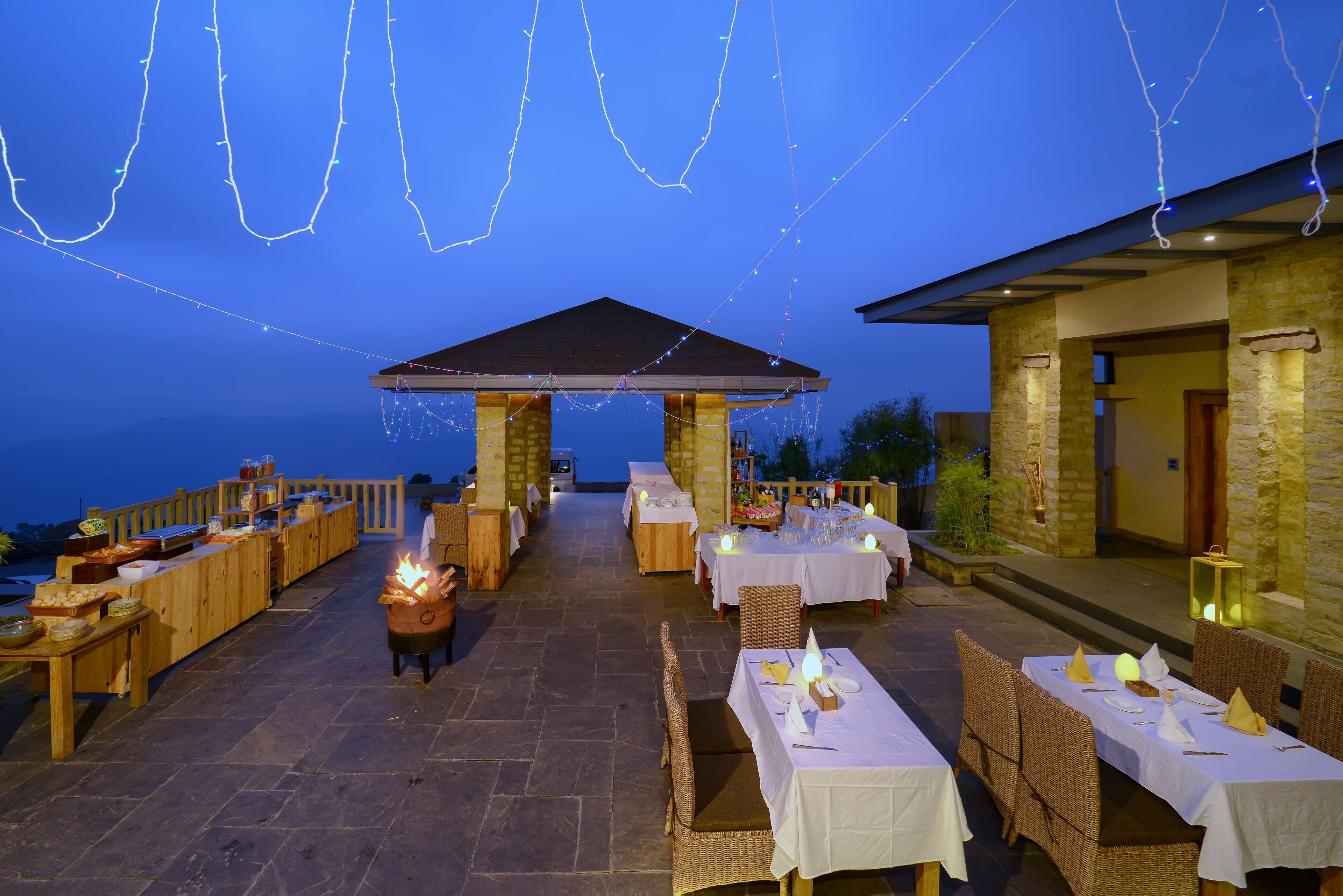 Een terras met eettafels, een overdekt zitgedeelte en sfeerverlichting.