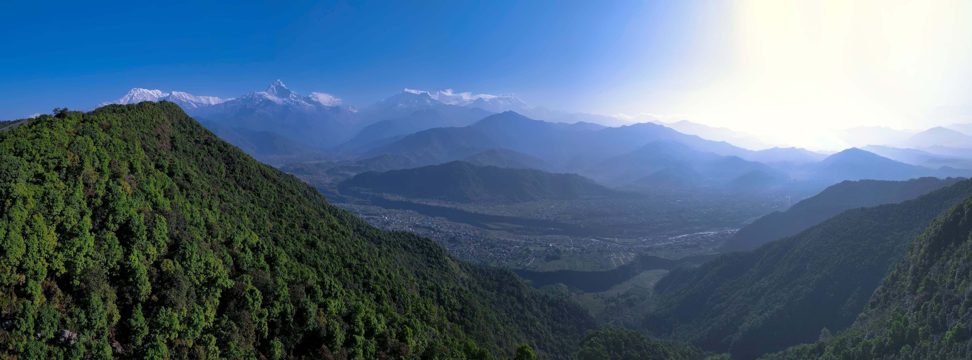 A mountainous landscape with dense forested areas and a valley below.