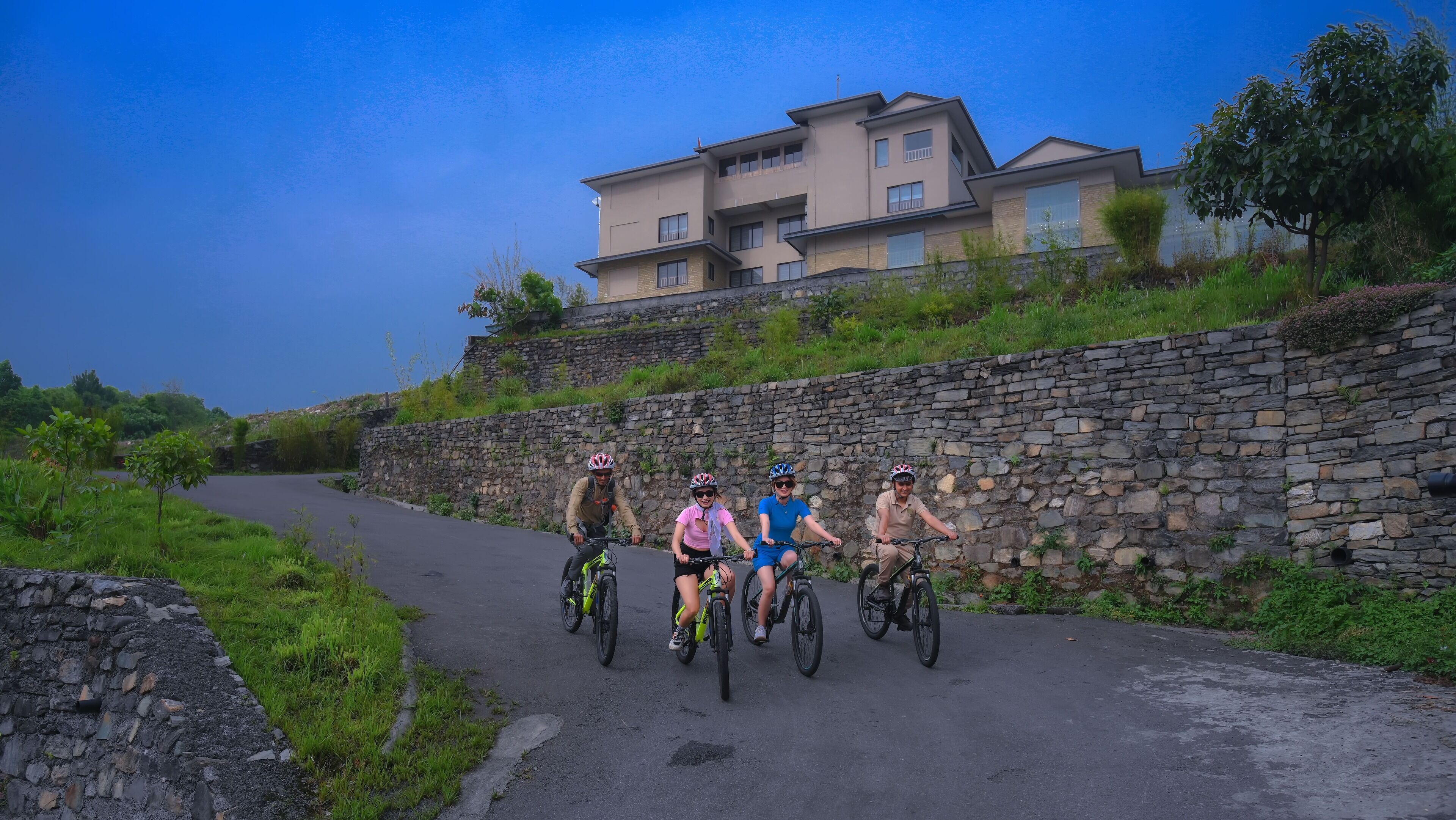 A paved road with a stone wall on one side and a modern house in the background.