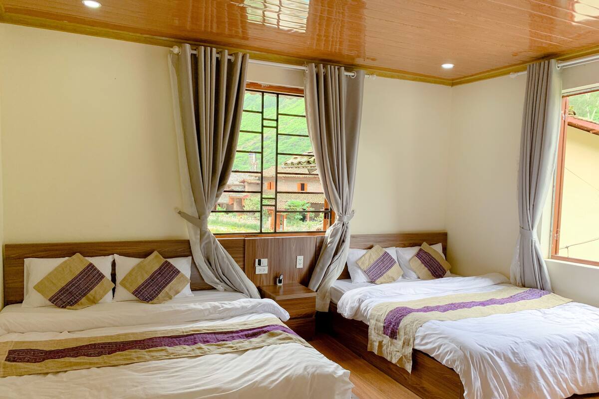 A hotel room with two beds, wooden headboards, and a window with curtains.