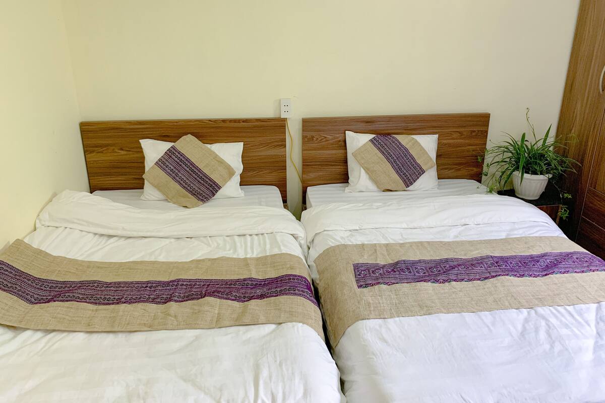 A double bed with a wooden headboard, two pillows, and a decorative throw.