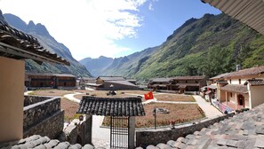 A traditional village with stone buildings, a central courtyard, and mountainous backdrop. - Meo Vac Valley Hotel - Hostel (Meo Vac)